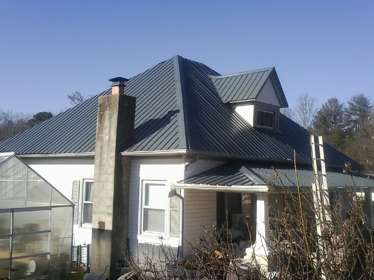 Dark blue standing seam metal roof on a white farmhouse with dormer — Slate & Tile Roof Repair by Roofing Brothers in Huntland