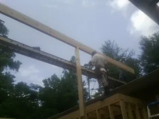 Carpenter setting a ridge beam over a new addition frame — Ice Dam Removal by Roofing Brothers in Huntland