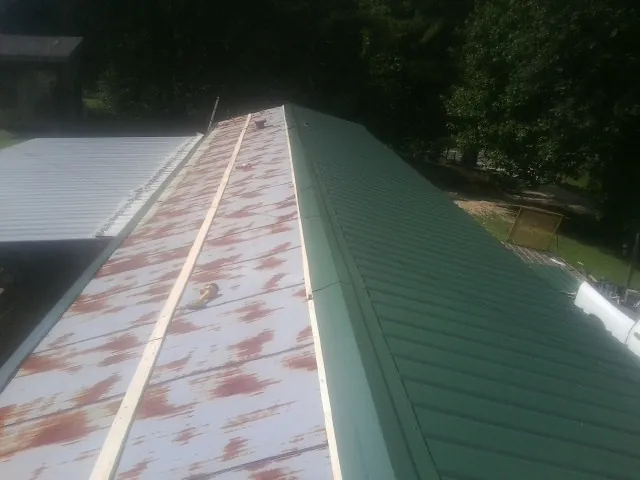 Old rusted panels beside newly installed green metal roofing — Wind Damage Roof Repair by Roofing Brothers in Huntland