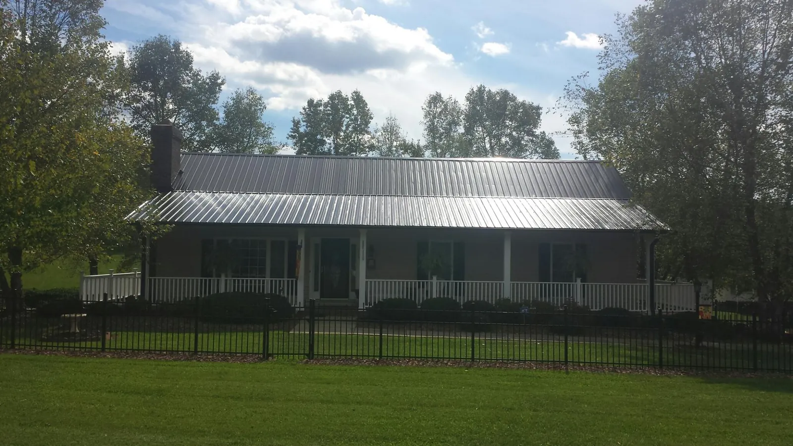 Gray metal roof on a brick ranch with a full width front porch — Gutter Guard Installation work by our crew in Huntland
