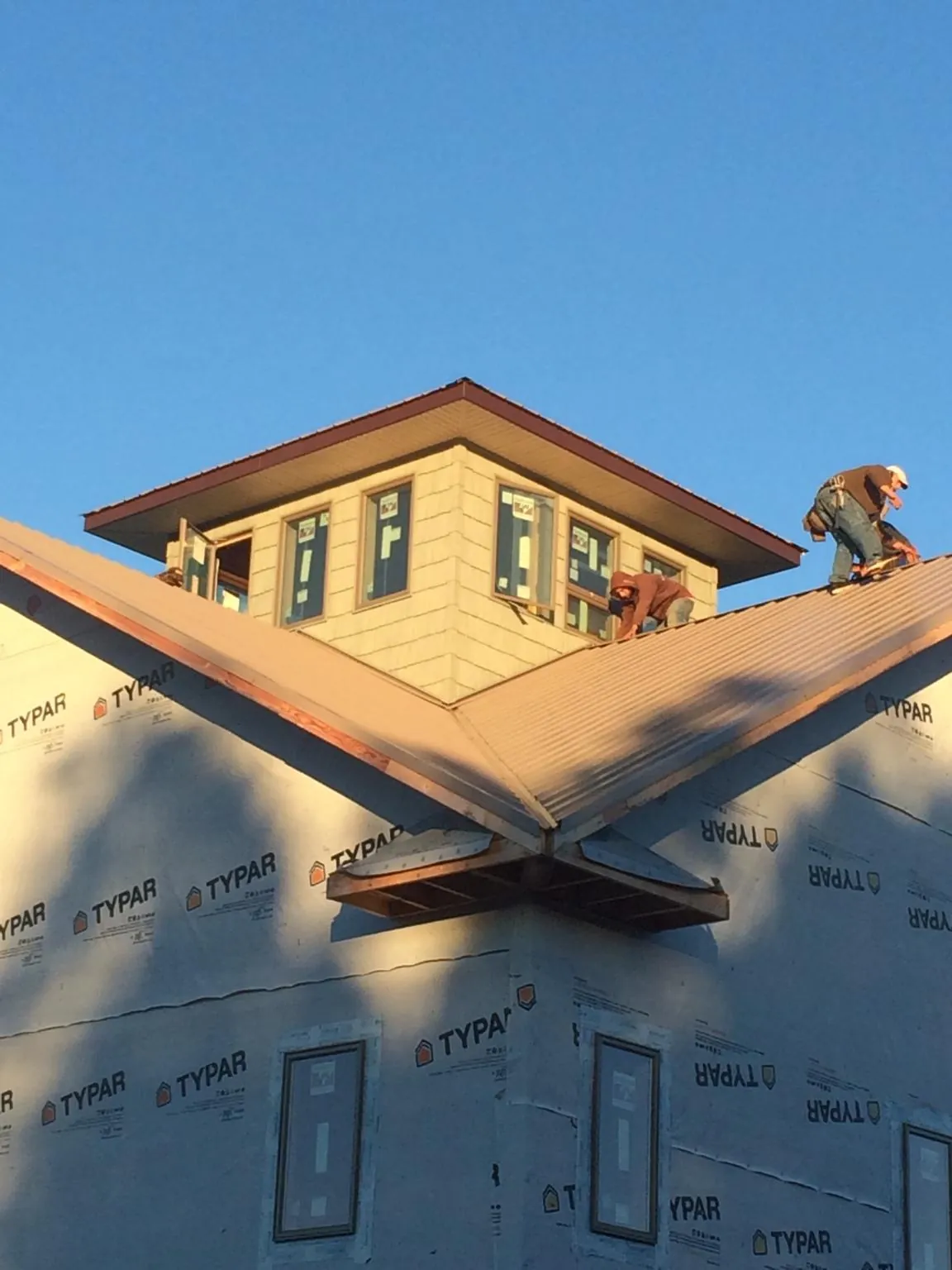 Roofers working around a rooftop cupola on a new metal roof at sunset — Roof Waterproofing in Huntland by Roofing Brothers